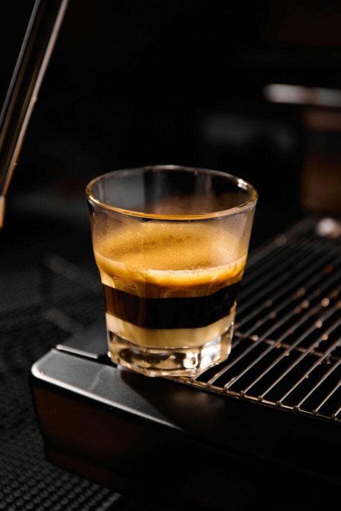 Primer plano detallado de la extracción de café de especialidad goteando de forma pausada dentro de una jarra de cristal.
